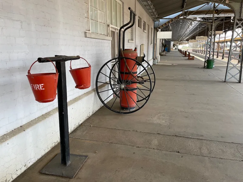 Historic wheeled firefighting equipment and red fire buckets on Platform 1 at Kimberley Railway Station. 