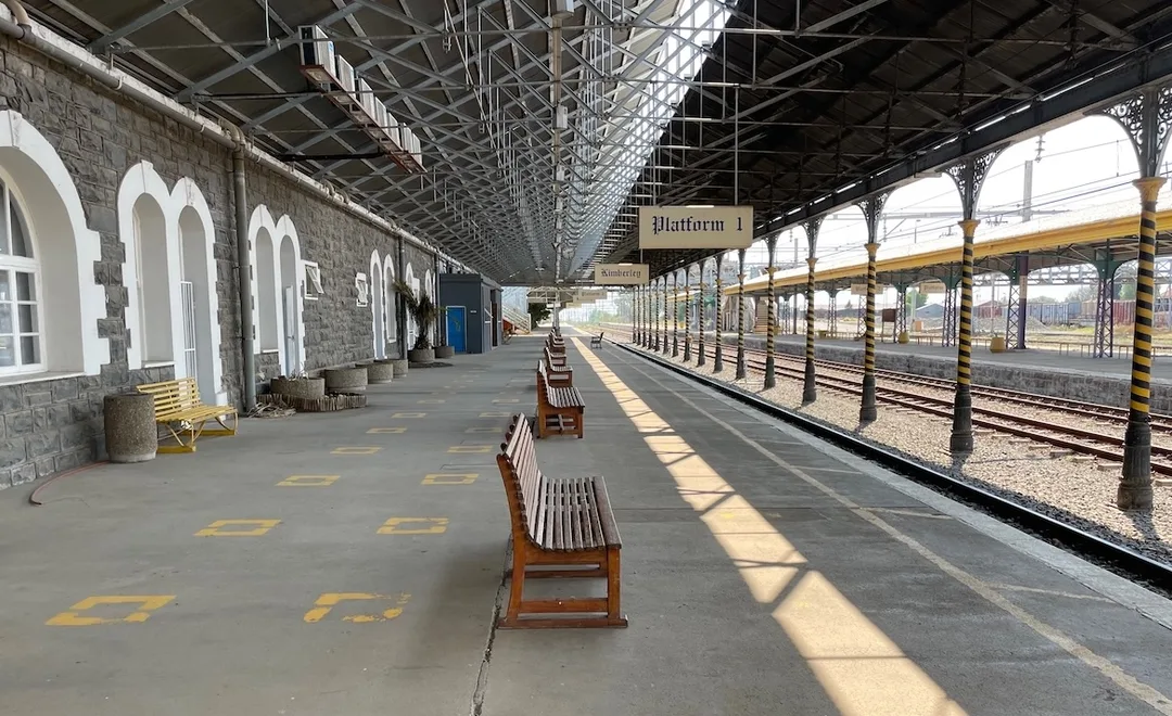 View along Platform 1 at Kimberley Railway Station showing the historic canopy, station signs, benches and railway tracks.
