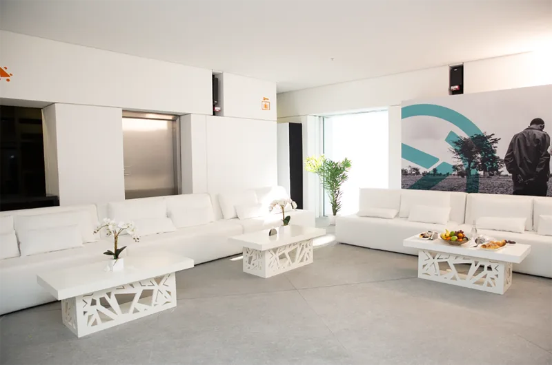 White hospitality lounge with custom scenic furniture and branded graphic backdrop at Louvre Abu Dhabi