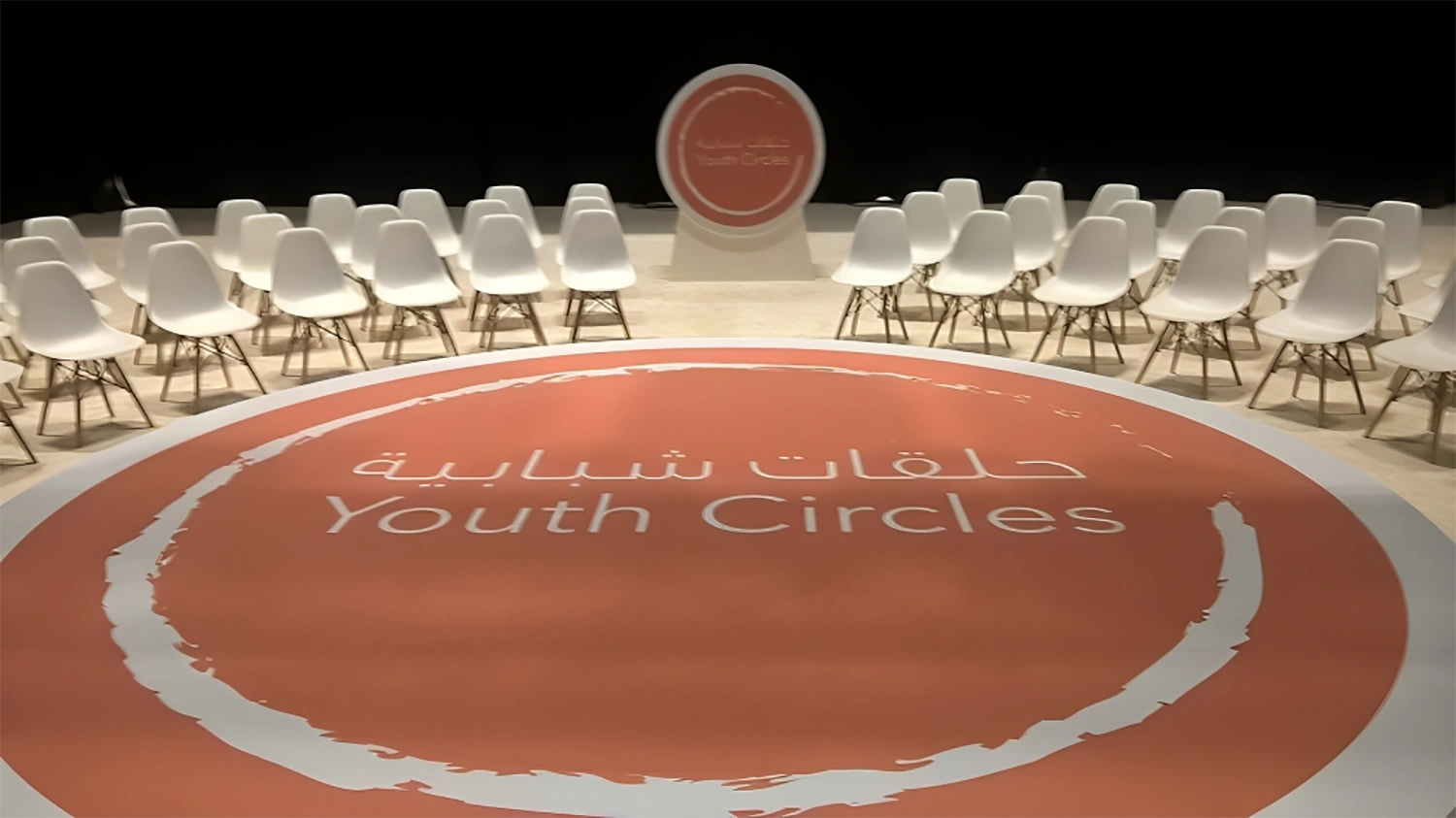White perimeter stage construction surrounding the central orange branded floor treatment.
