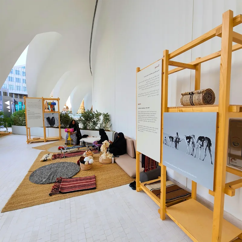 Open timber display bays combining shelving, archive photography and cultural objects.