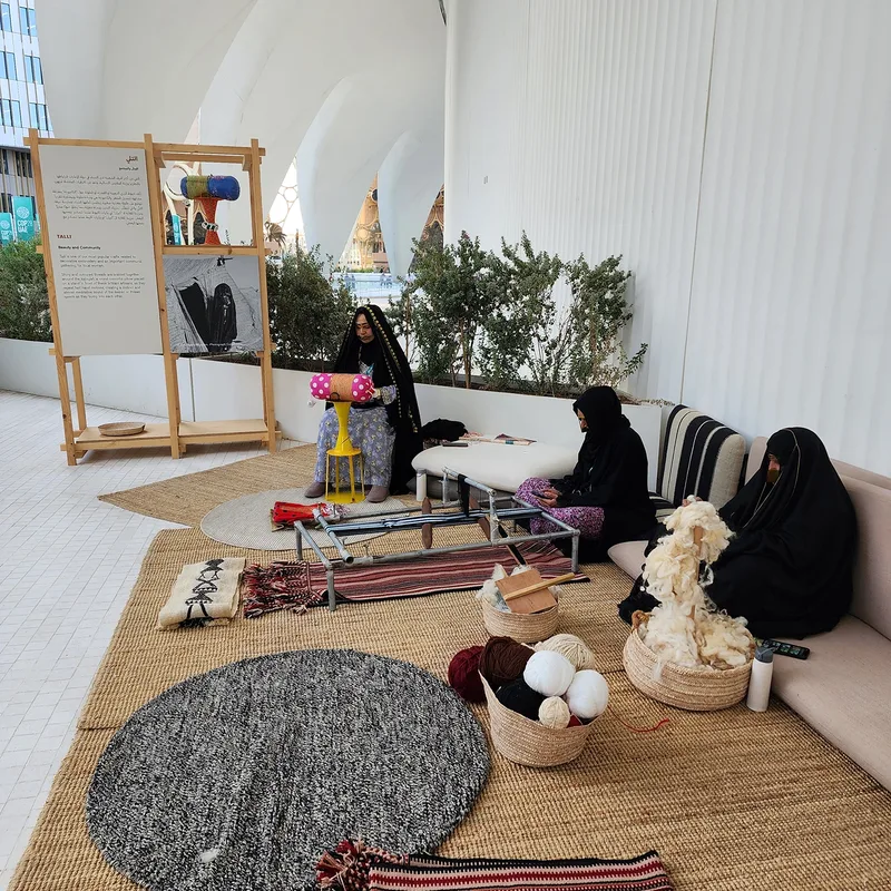 Stained timber shelving displaying woven cultural objects within the UAE Pavilion installation.