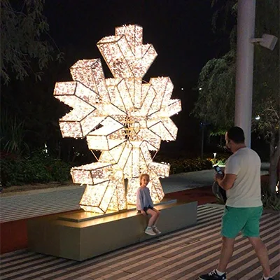 Refurbished illuminated snowflake sculpture positioned on a large public-realm scenic base.