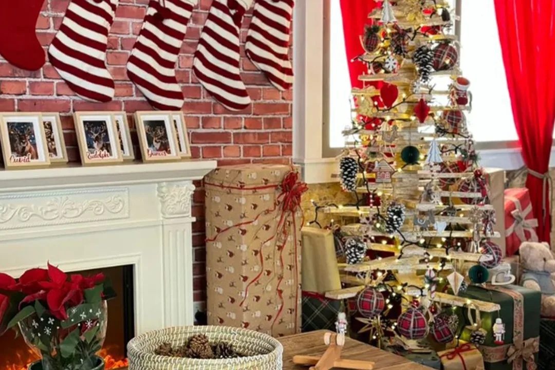 Scenic Christmas tree, wrapped presents and fireplace installation inside the temporary house.