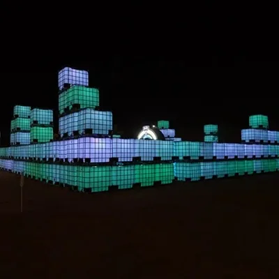 Illuminated IBC container maze with stacked modular towers at LIV Golf Riyadh 2025.