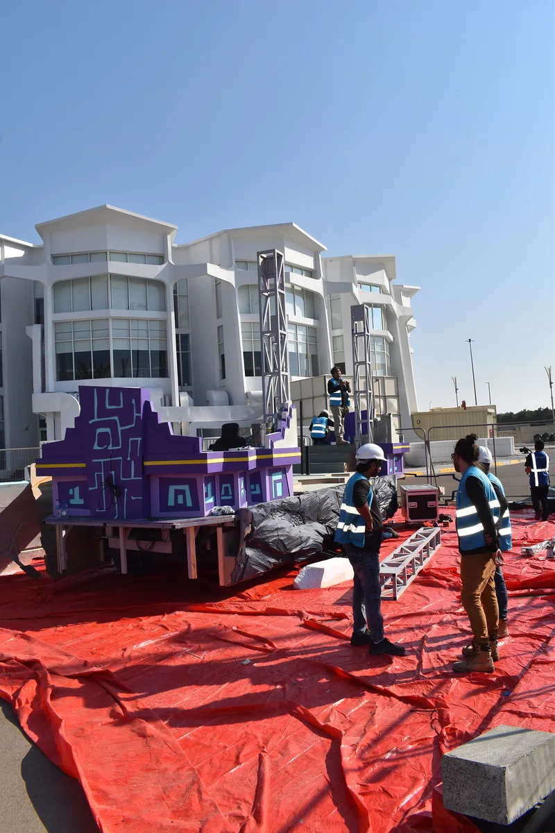 Purple patterned scenic panels and lightweight decorative construction being assembled around the parade truck.