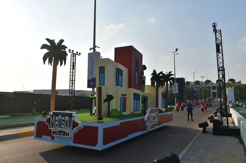 Completed purple Mansour Festival gateway float with dimensional branding, tall pillars and rock-effect base.