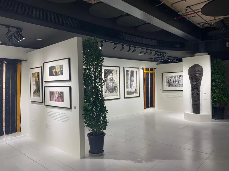 White modular exhibition partitions displaying framed cultural artwork and textile installations.