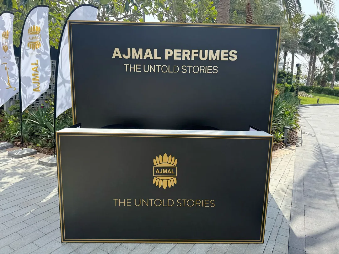 Gold vinyl Ajmal Perfumes branding applied across the black scenic registration structure.
