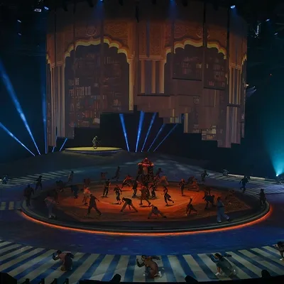 Wide view of performers on the circular Terhal stage beneath suspended scenic architecture.