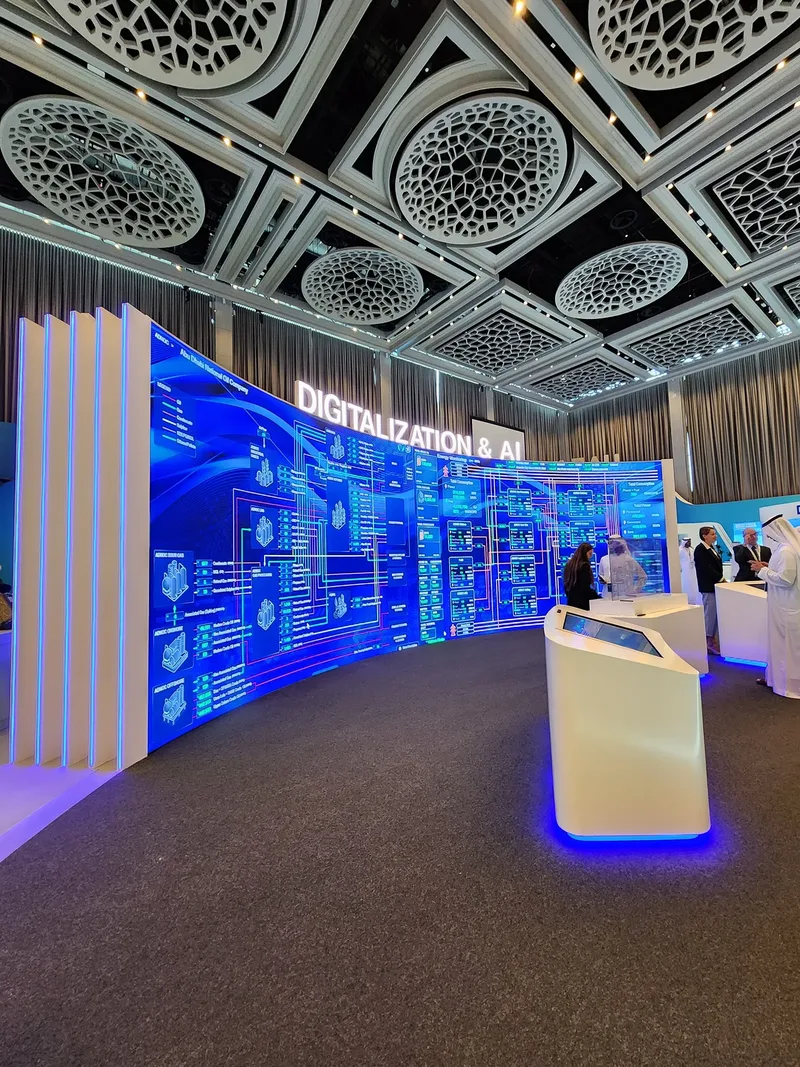 Curved exhibition environment fabricated around embedded LED screens and branded wall graphics.