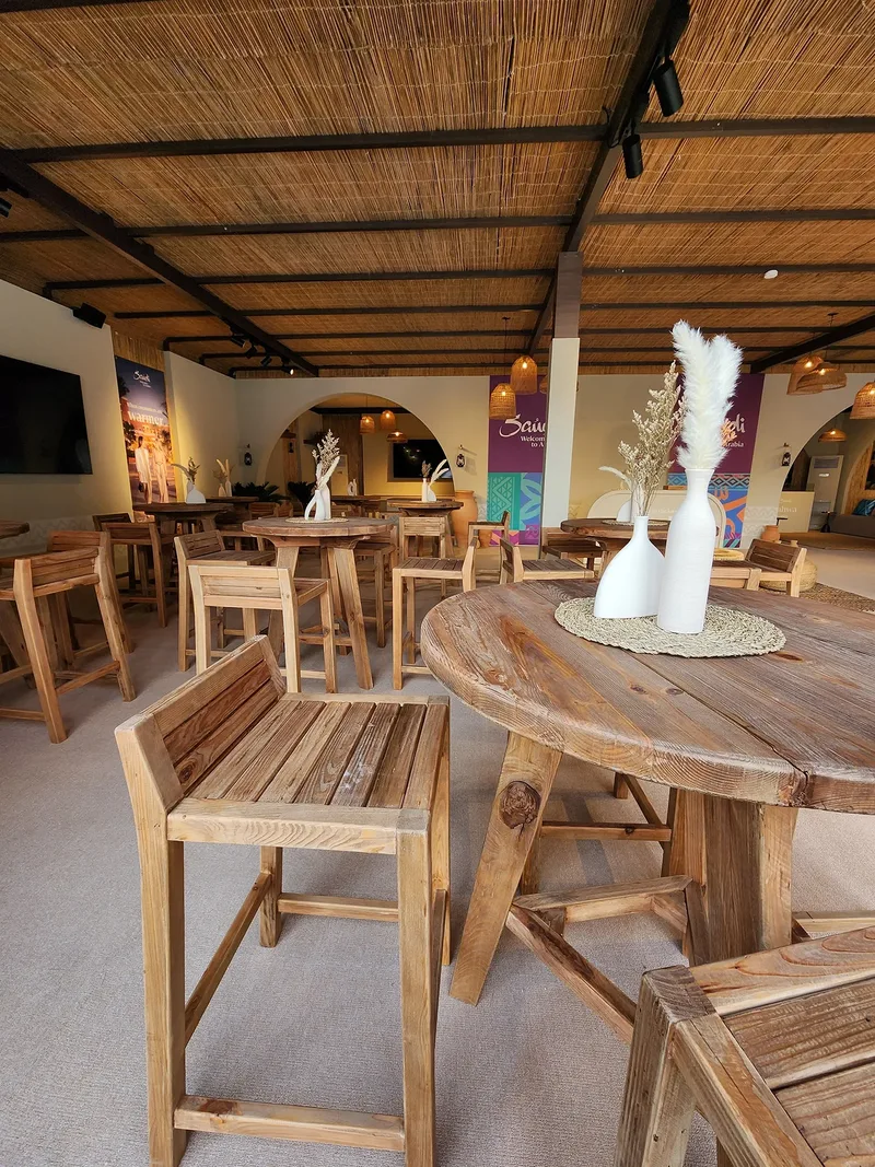 Outdoor high tables with Arrow barstools beneath cantilever umbrellas at the entrance.