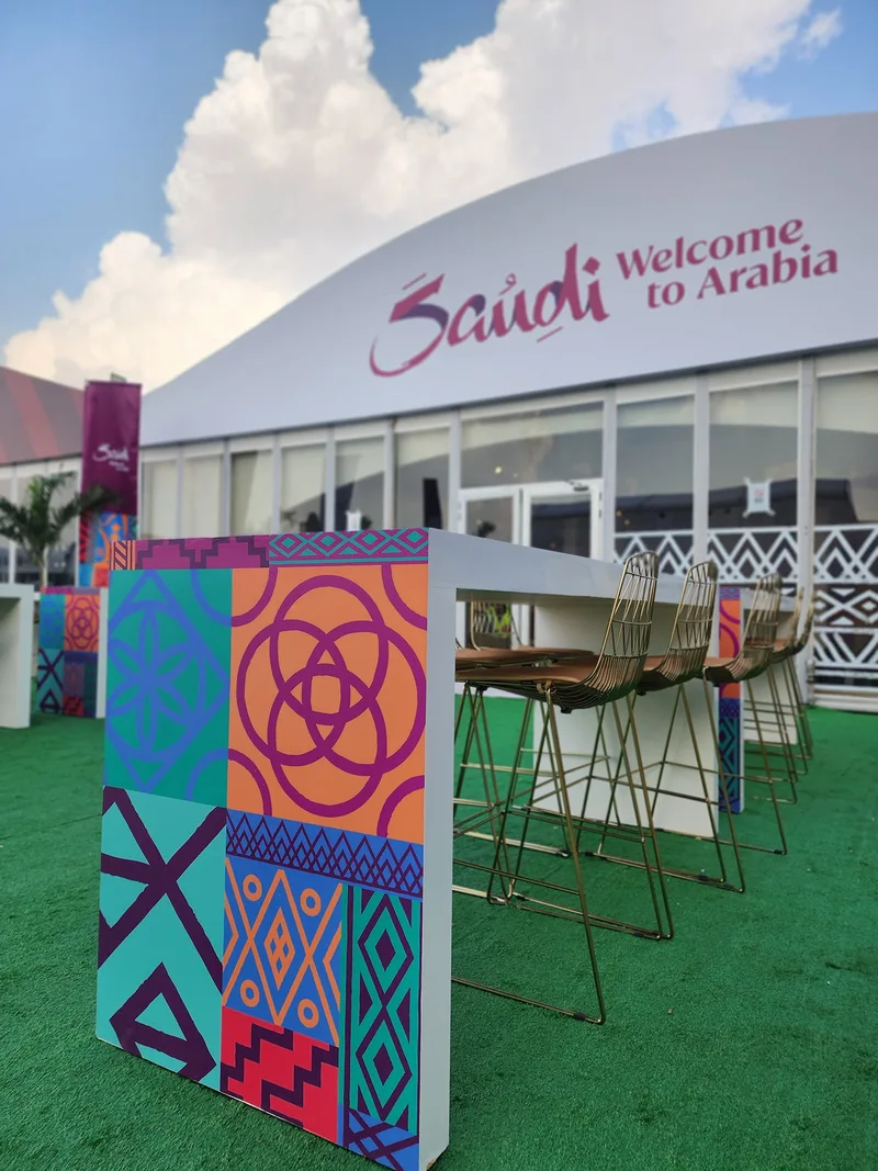 Main hospitality tent with natural timber tables, sofa seating and selected carpet.