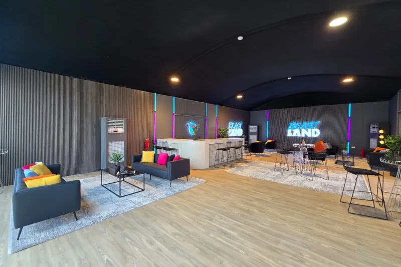 Indoor hospitality lounge with contemporary seating, tables and branded event graphics.