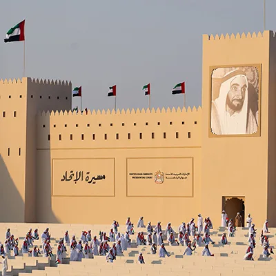 UAE cultural event setting with traditional architectural façade, national flags and heritage-inspired design.
