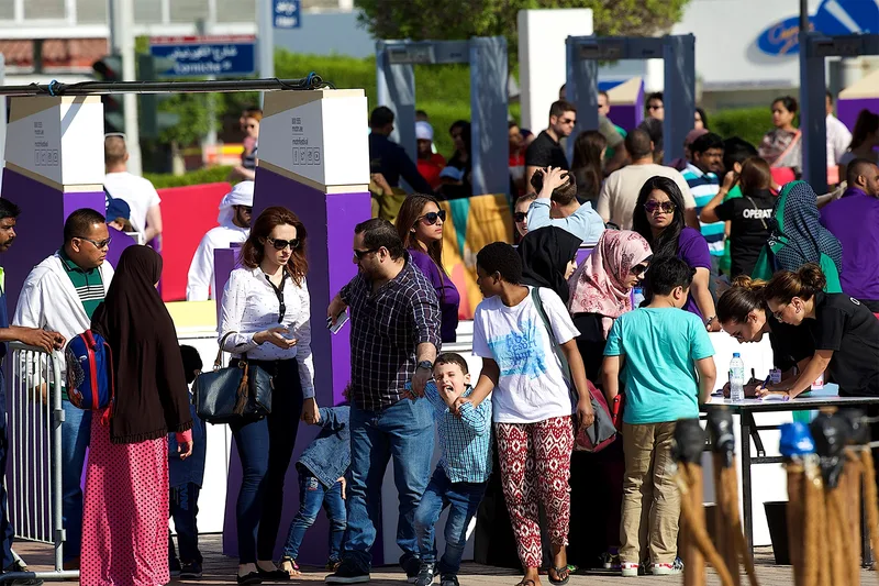 Crowds moving through a managed public event environment with temporary barriers, access control and visitor facilities.