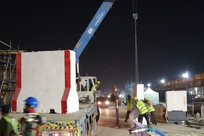 Crane lifting temporary event infrastructure during night installation