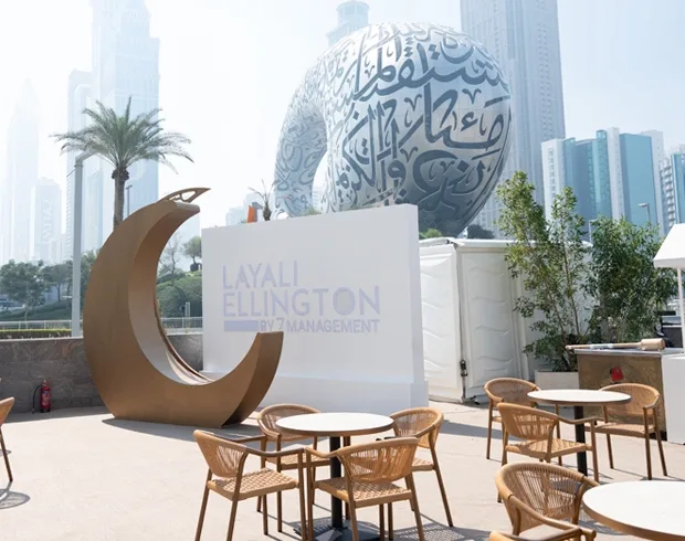 Outdoor hospitality environment with branded feature, café seating and Dubai skyline backdrop.