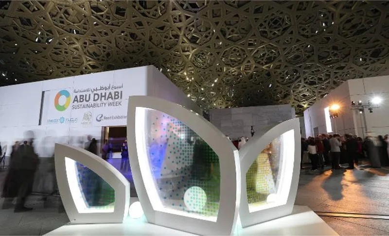 Branded Abu Dhabi Sustainability Week installation at Louvre Abu Dhabi with illuminated scenic structures and event graphics