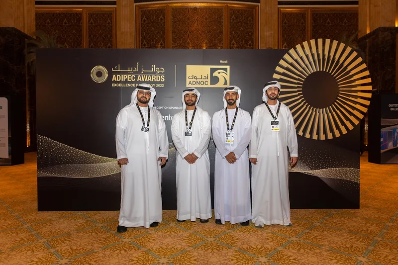 ADIPEC Awards 2022 delegates in front of the branded ADNOC awards backdrop at a formal event in Abu Dhabi