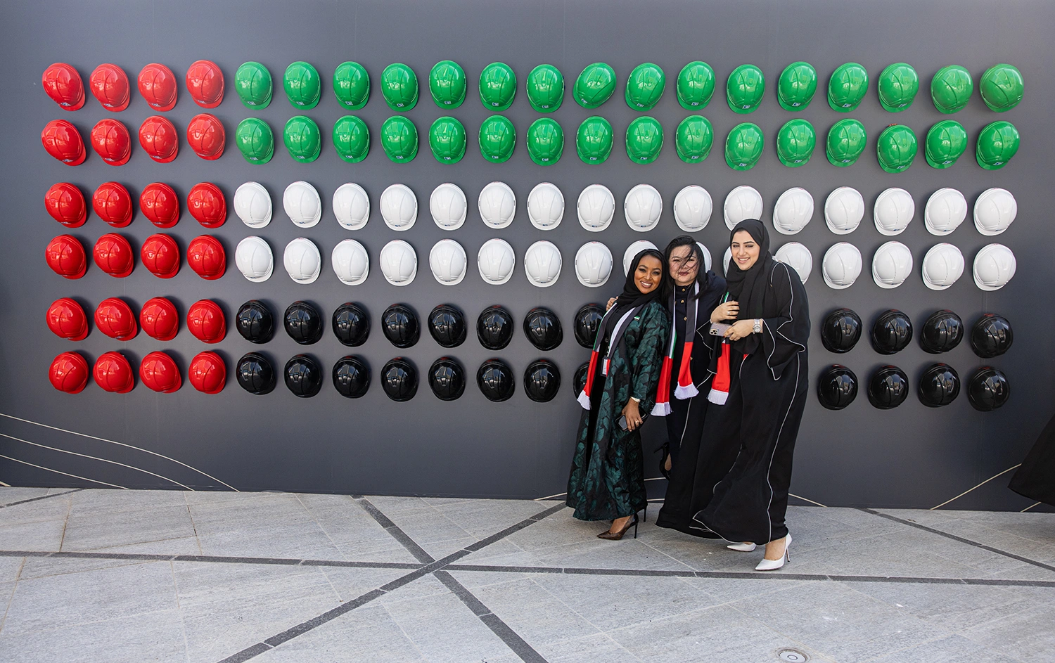 Guests at the ADNOC Jubilee UAE 50th National Day event in front of a red, green, white and black hard-hat installation