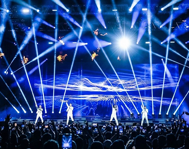 Live concert performance with large LED screen, dramatic stage lighting and audience at a major event
