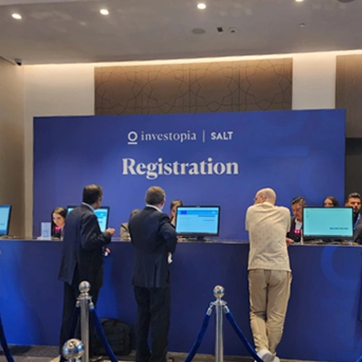 Investopia conference registration desk with delegates checking in at a branded event entrance