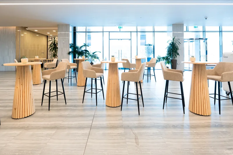 ENACT Majlis networking area with high tables, bar stools, natural finishes and daylight-filled hospitality space