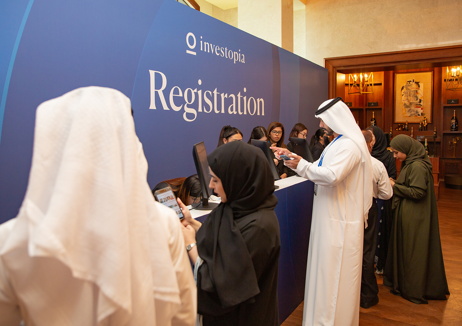 Investopia registration desk with branded backdrop, digital check-in screens and arriving delegates