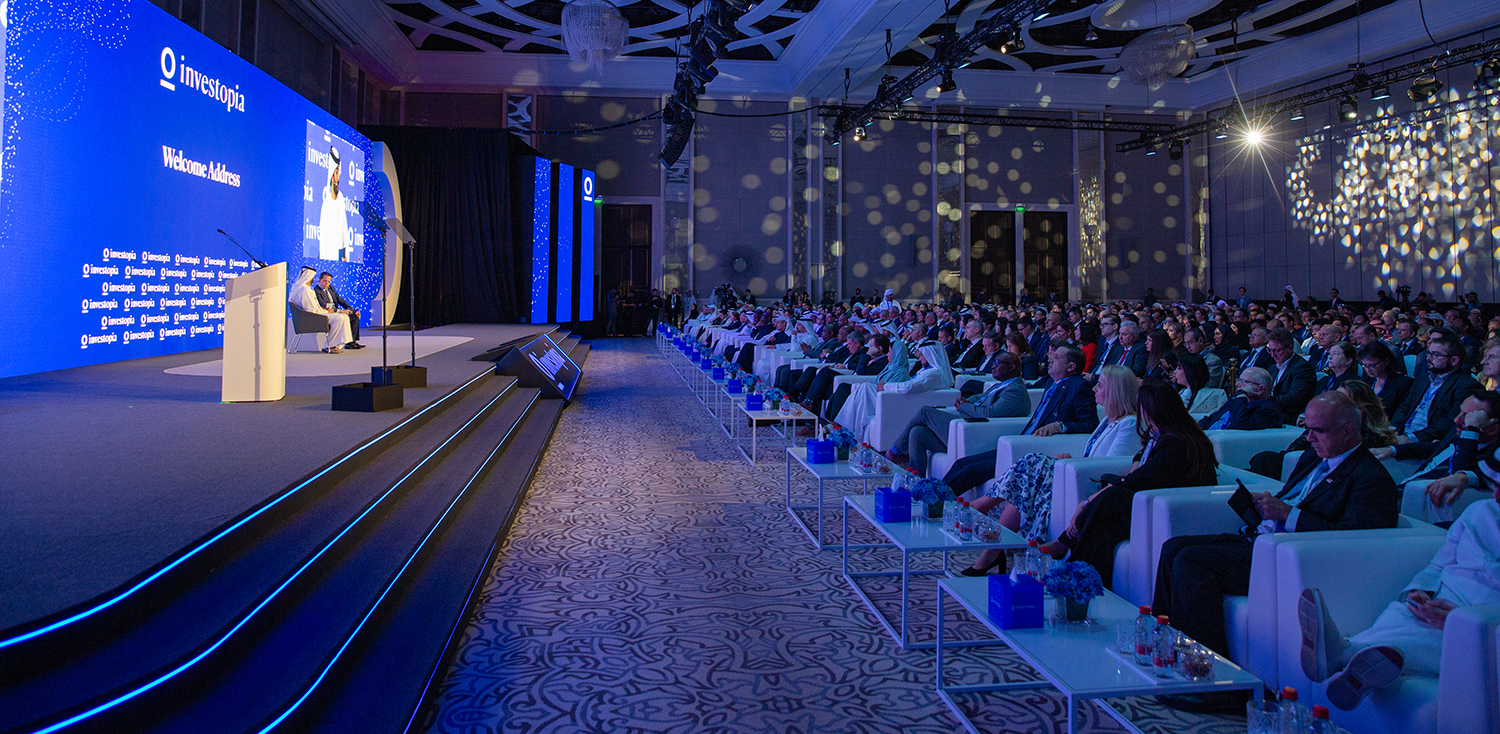 Wide-angle auditorium view showing full capacity audience during economic keynote address