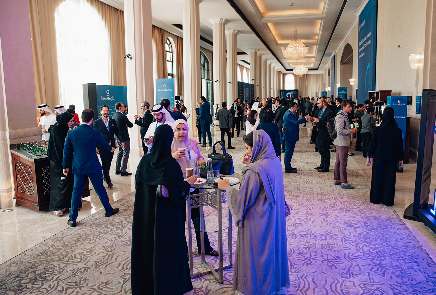 Investopia networking foyer with delegates, hospitality stations and branded directional signage