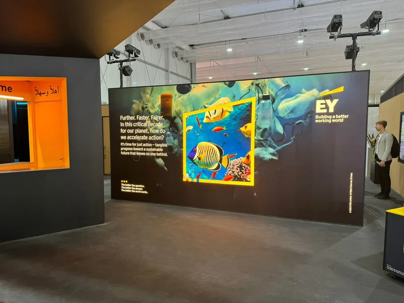 EY COP28 exhibition wall with large digital content display, branded environmental messaging and guest viewing area