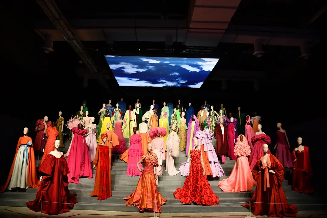 Forever Valentino fashion exhibition in Doha with Valentino couture garments arranged across a dramatic tiered gallery display