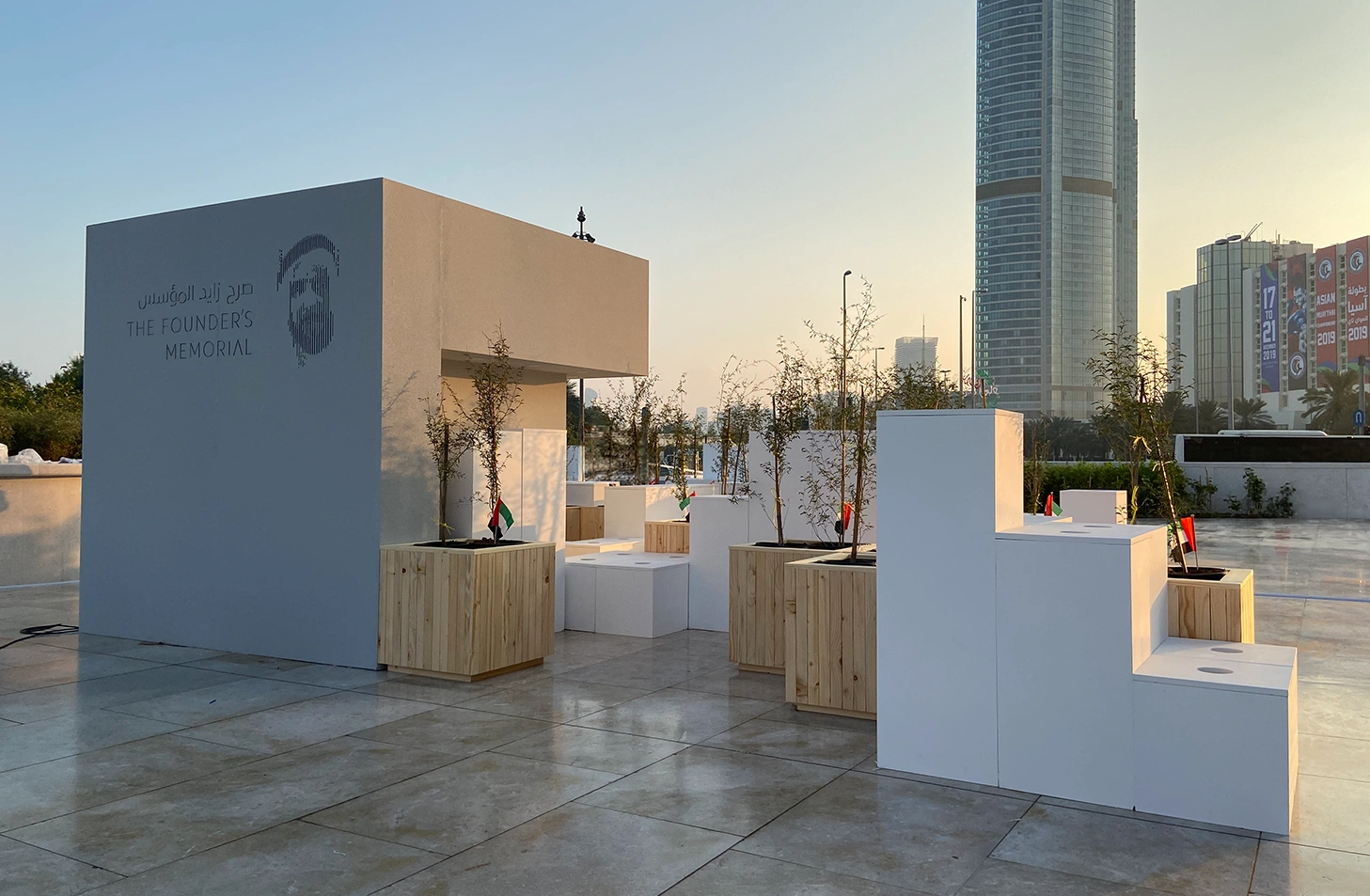 Founder’s Memorial National Day activation in Abu Dhabi with white scenic structures, planted ghaf trees and UAE flags