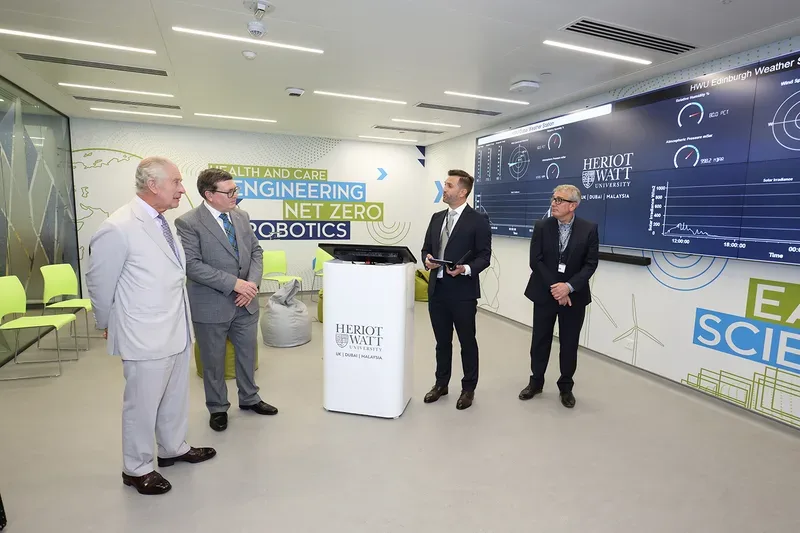 King Charles III attending a Heriot-Watt University climate technology presentation with researchers and digital monitoring displays during COP28 Dubai