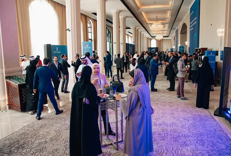 Investopia networking foyer with delegates, hospitality stations and branded directional signage