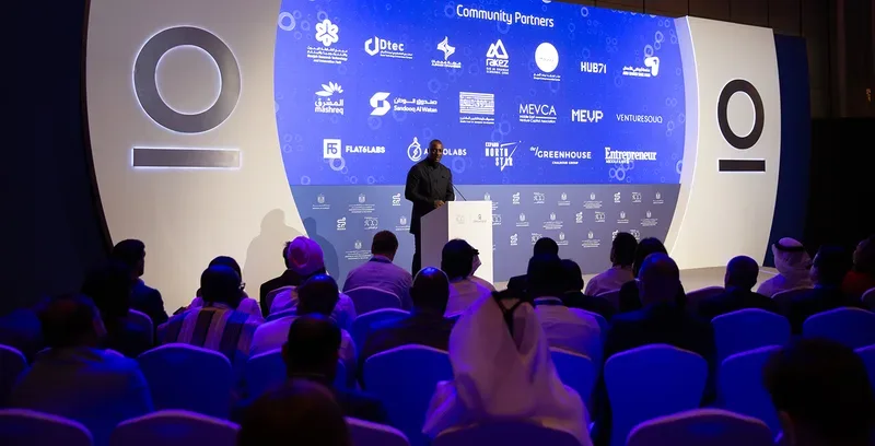 Global finance leaders presenting on illuminated stage set inside Dubai summit venue