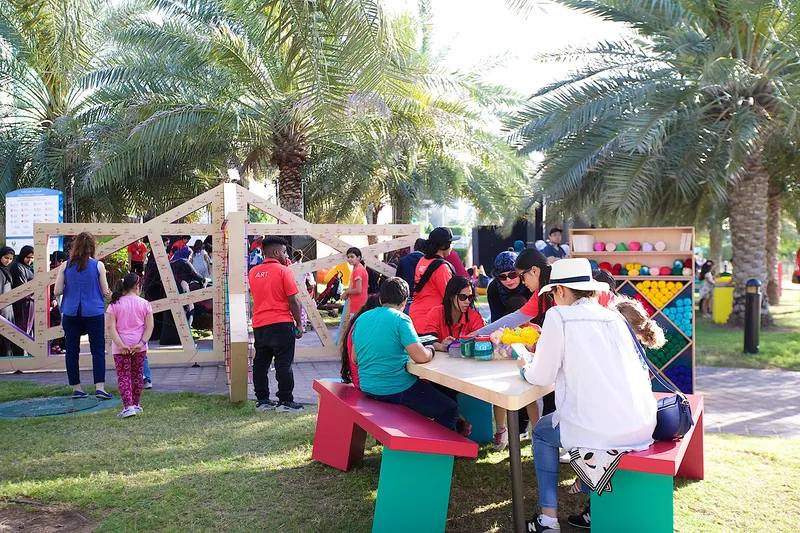 Family craft activity at Mother of the Nation Festival with children and parents gathered around an outdoor workshop table