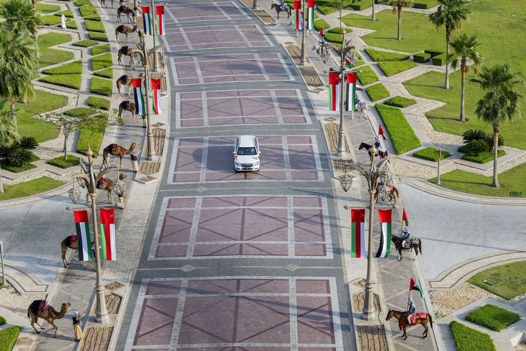 Official Oman state reception motorcade route in Abu Dhabi with ceremonial camels, mounted riders and UAE flags