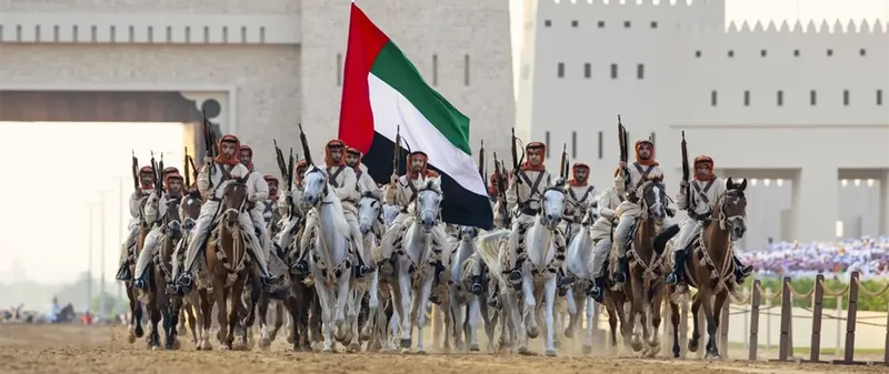 Mounted cultural procession at Union Parade 2025 with riders carrying a large UAE flag during the national celebration