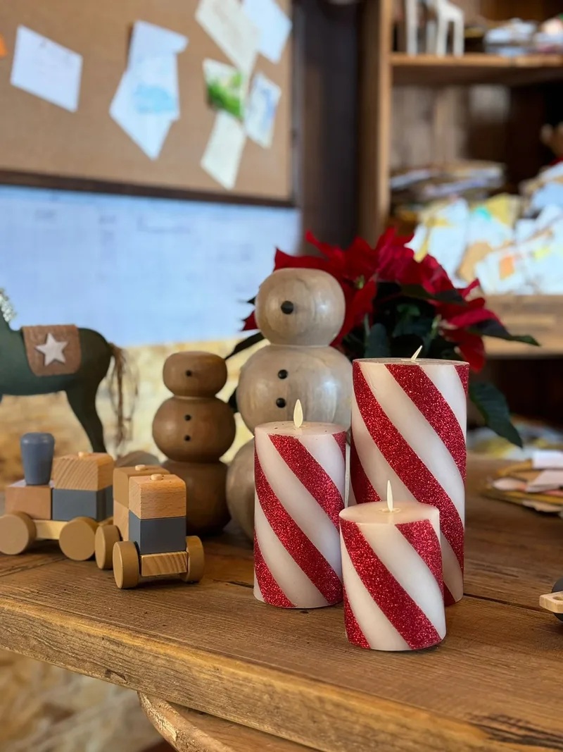 Sustainable Christmas décor with wooden toys, handmade ornaments and red-and-white striped candles inside Santa’s house