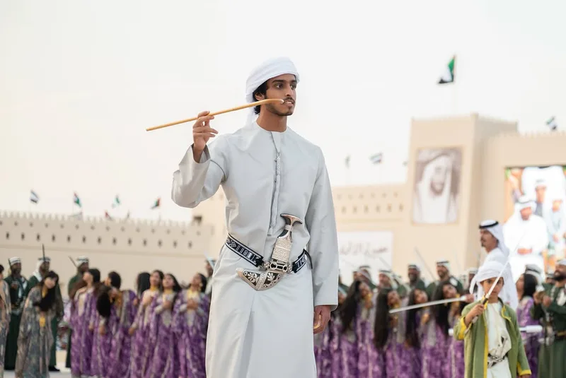Emirati cultural performer at Union Parade 2025 in traditional dress holding a ceremonial stick during the public celebration