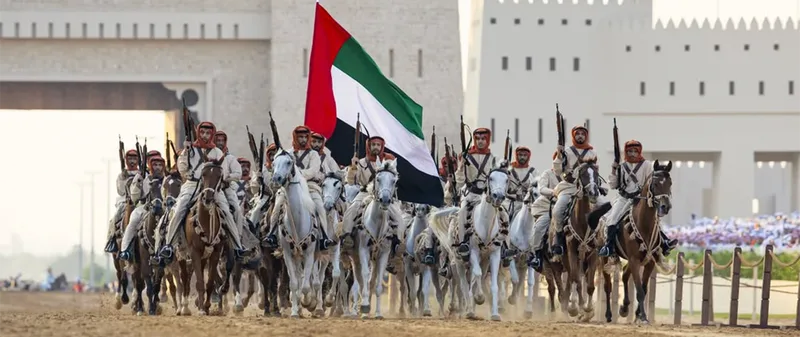 Mounted cultural procession at Union Parade 2025 with riders carrying a large UAE flag during the national celebration