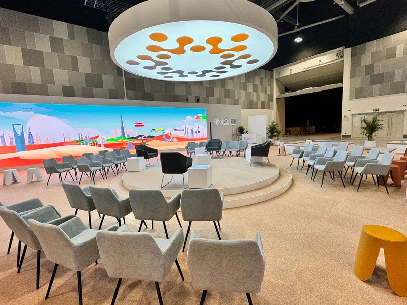 Large event venue divided into comfortable hospitality zones using sofas and lounge furniture.