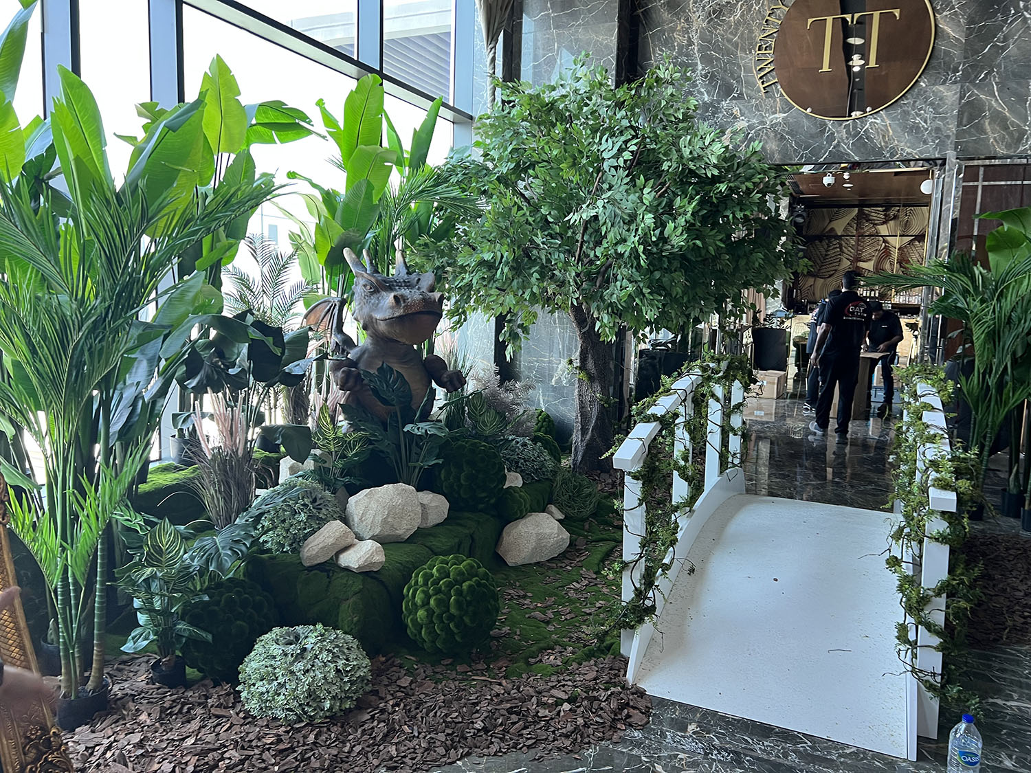 Giant dragon character prop emerging from dense foliage and woodland styling at EINO Dubai.