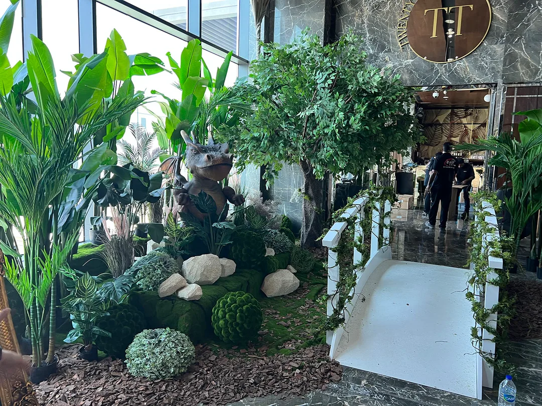 Giant dragon character prop emerging from dense foliage and woodland styling at EINO Dubai.
