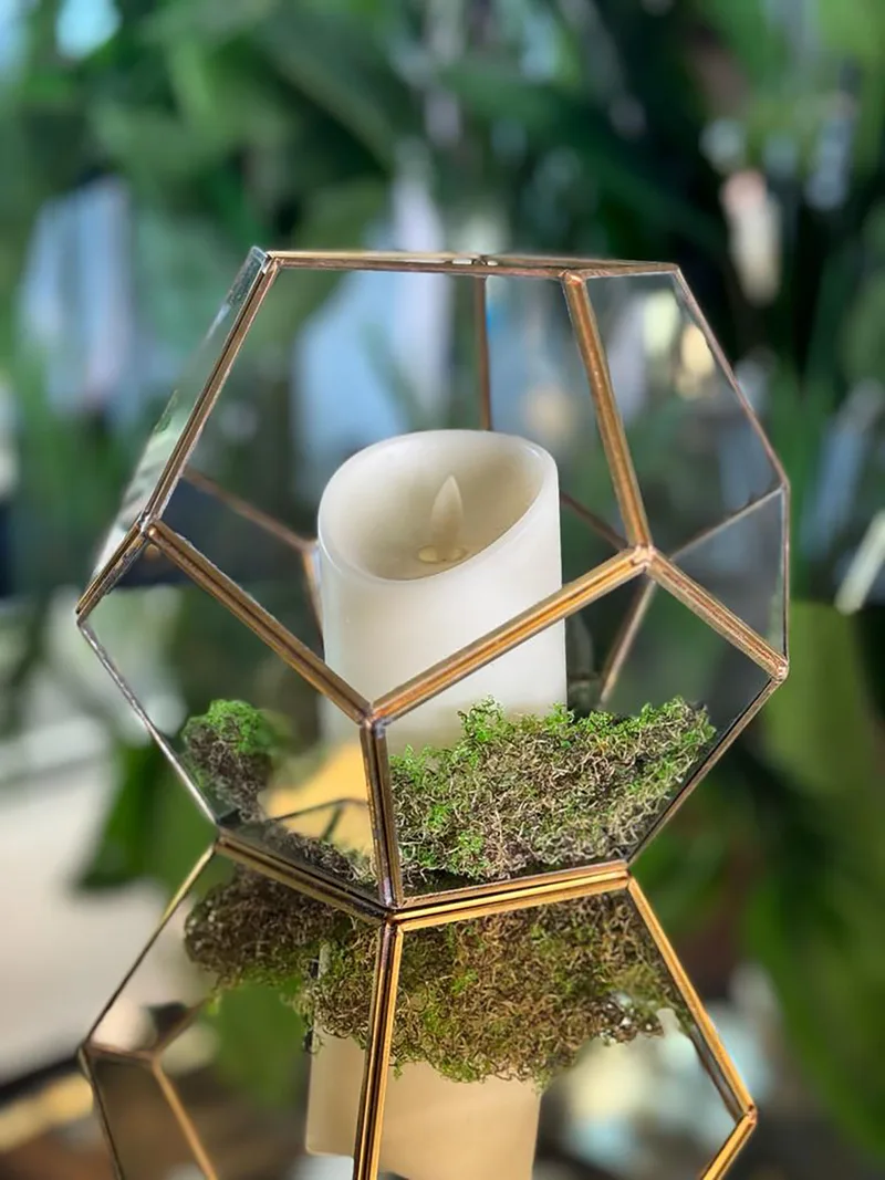 Geometric glass candle lantern with preserved moss used as an enchanted forest table accessory.