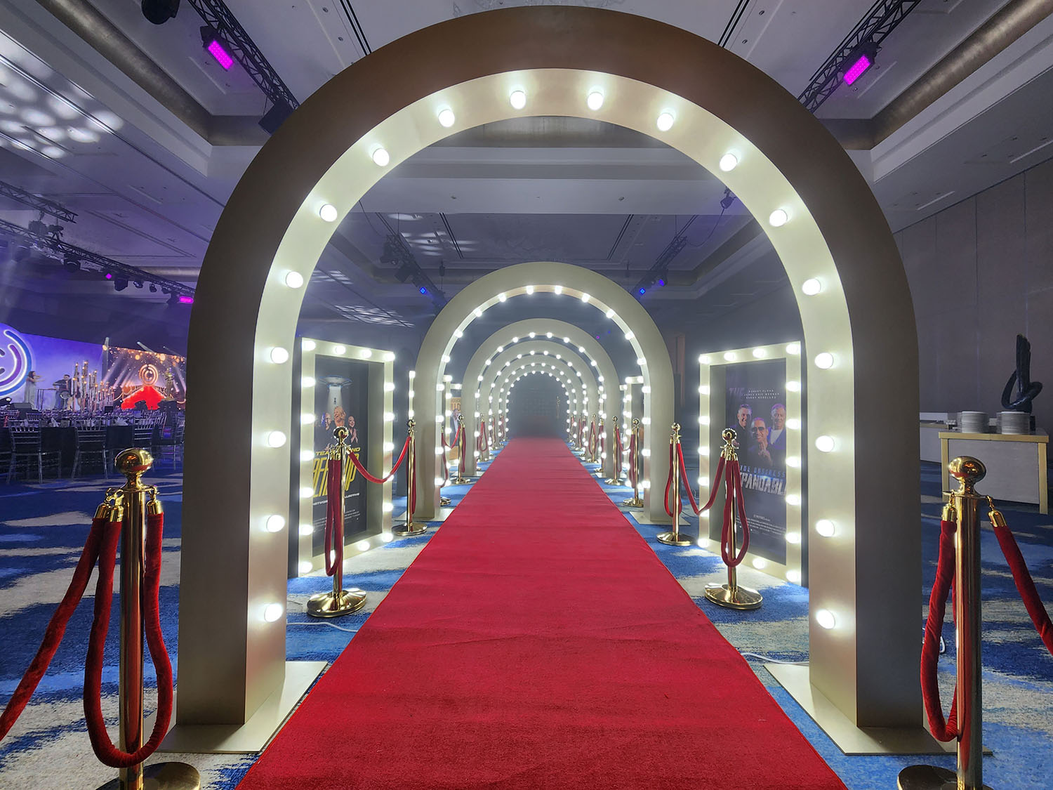 Repeated Hollywood light arches forming an immersive red carpet tunnel through the ballroom.