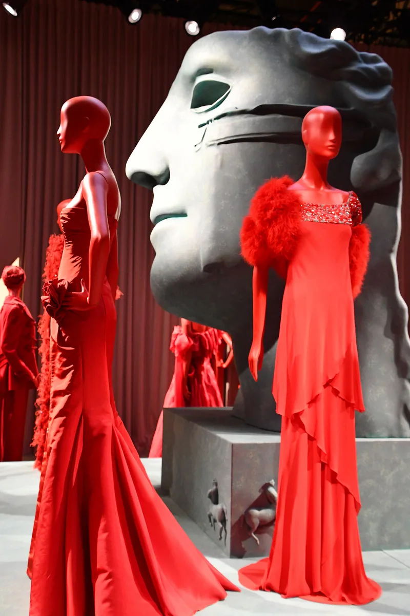 Sculptural face installation surrounded by red mannequins and coordinated fashion displays in Doha.