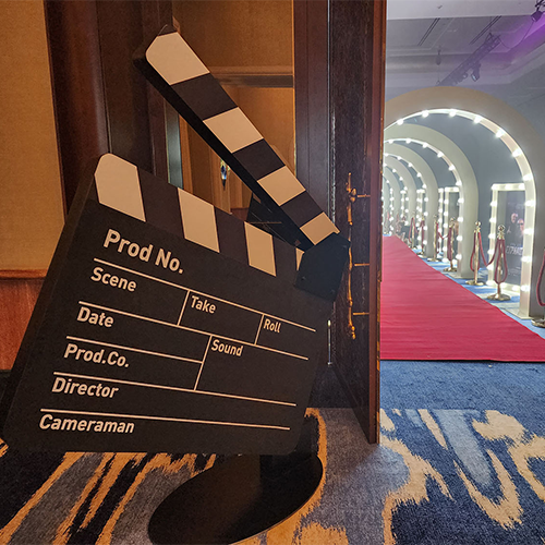 Evolution Prop Shop oversized movie clapperboard beside the Hollywood-themed entrance installation.